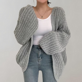 Dame i oversized strikcardigan med ribstruktur og lange ærmer