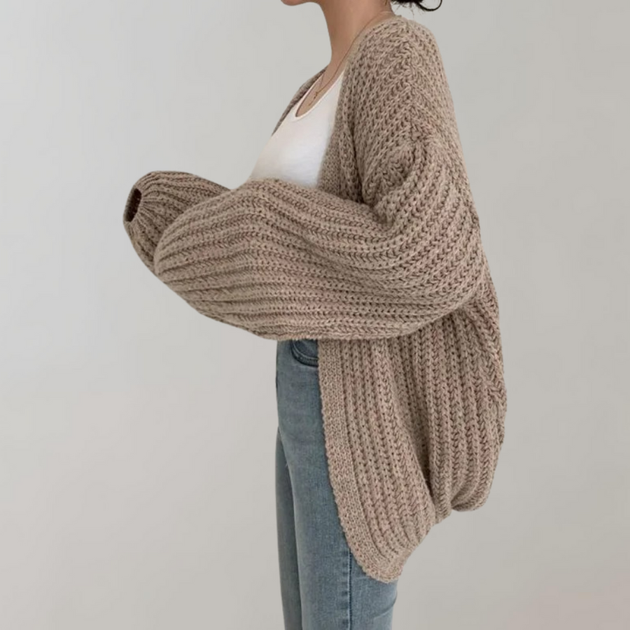 Dame i oversized strikcardigan med ribstruktur og lange ærmer