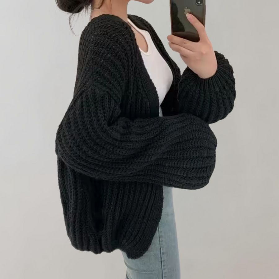 Dame i oversized strikcardigan med ribstruktur og lange ærmer