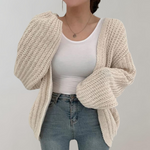 Dame i oversized strikcardigan med ribstruktur og lange ærmer